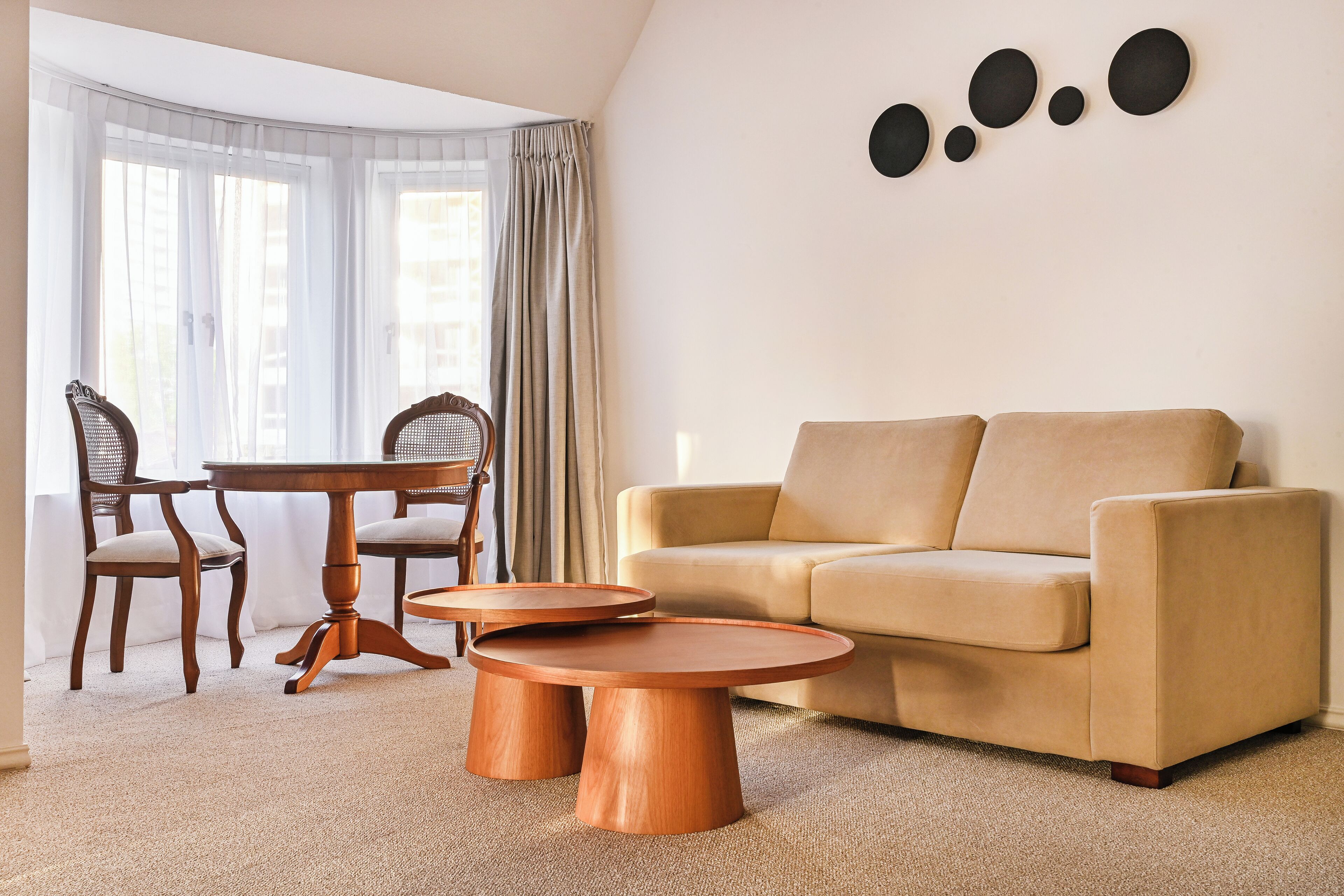 A living room with a beige sofa, two wooden coffee tables, and a dining area with a wooden table and chairs.