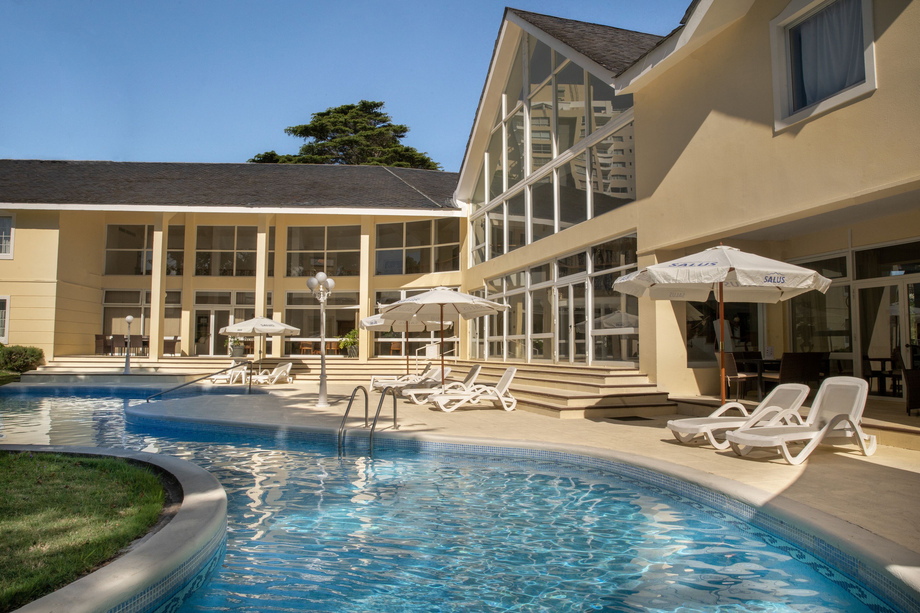 Una piscina al aire libre, sillones reclinables de piscina