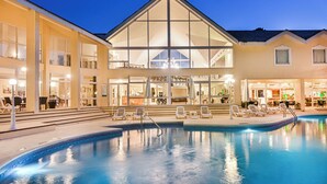 Un hôtel doté d’une piscine, d’un espace extérieur aménagé et d’une grande façade vitrée.