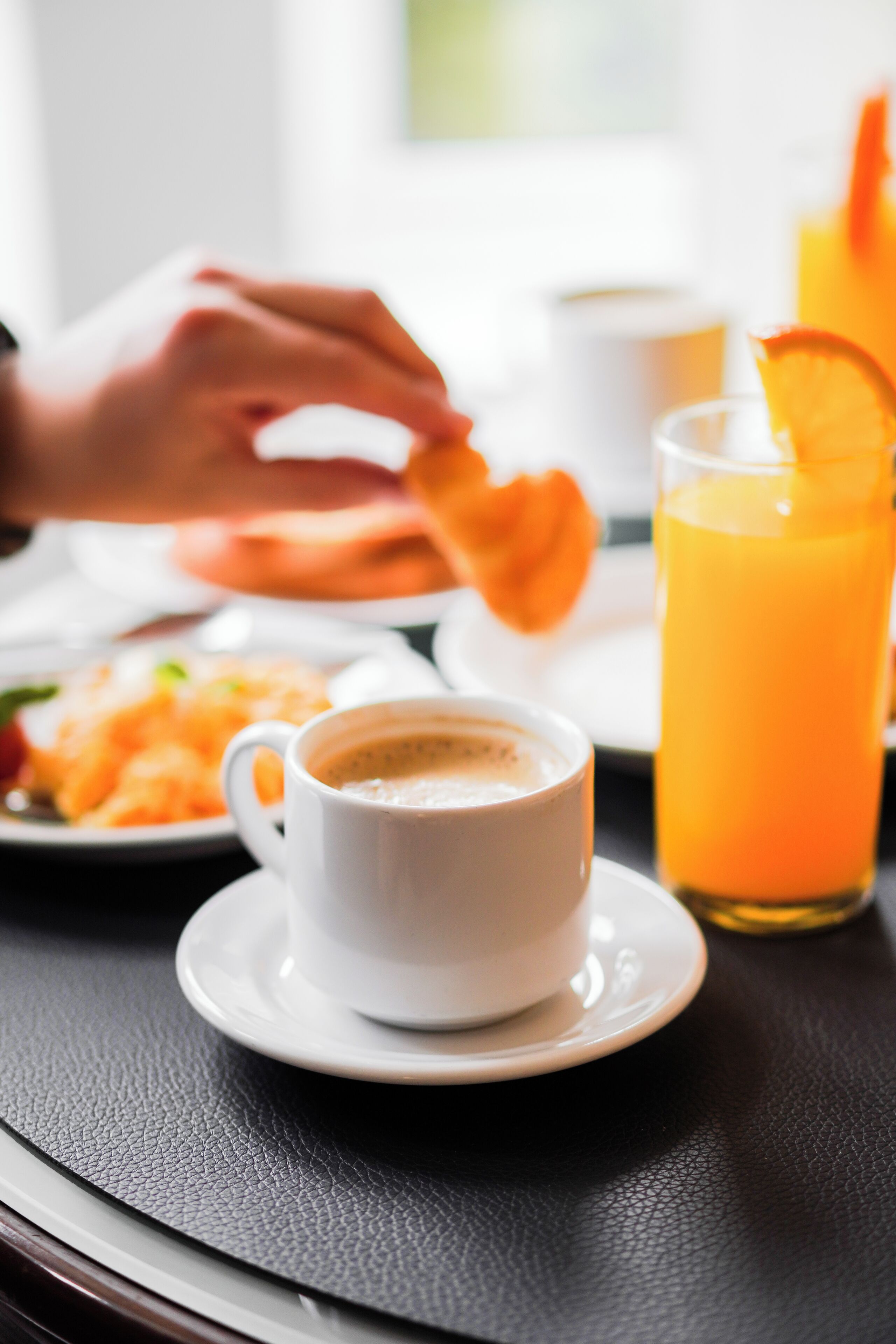 A breakfast setting with a cup of coffee, a glass of orange juice, and a plate of food.