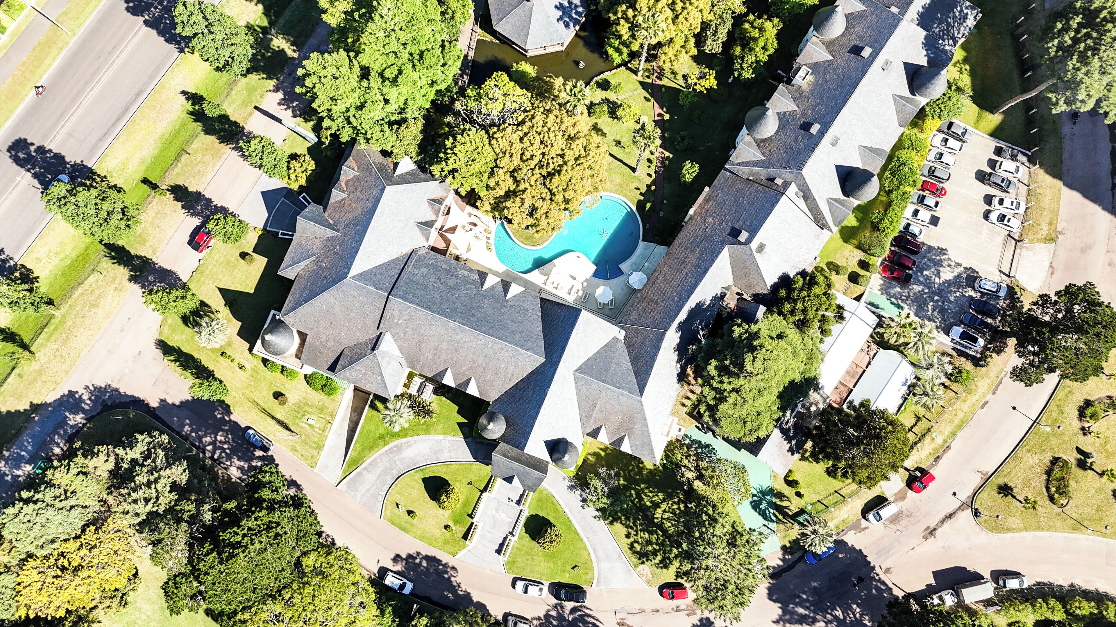 An aerial view of a property with a swimming pool, multiple buildings, and a parking lot.