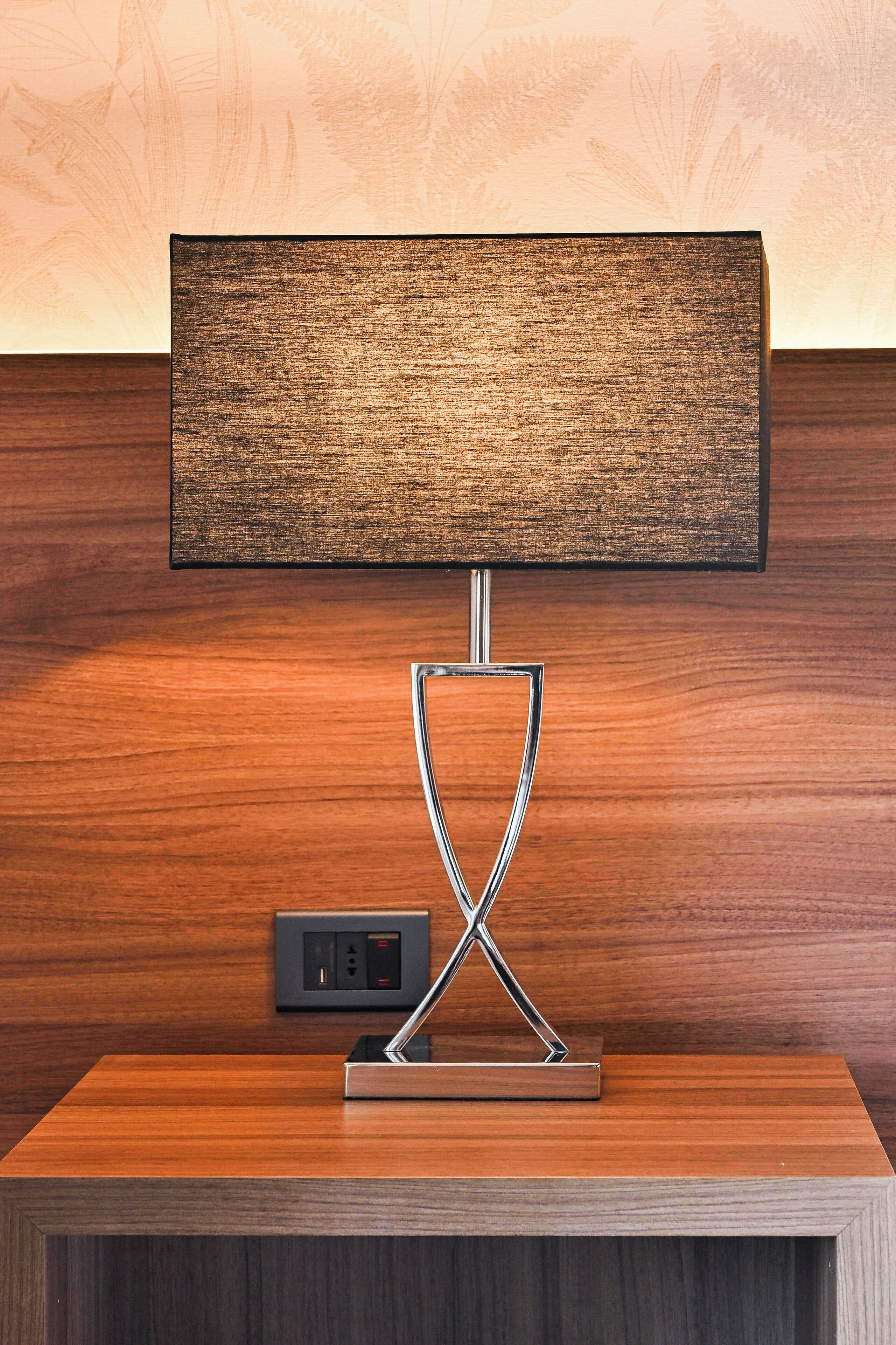 A modern lamp with a rectangular shade on a wooden nightstand.