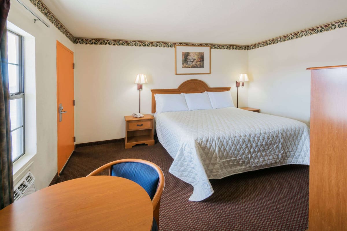 Ein Hotelzimmer mit Bett, Nachttischlampen, Schreibtisch und Stuhl.