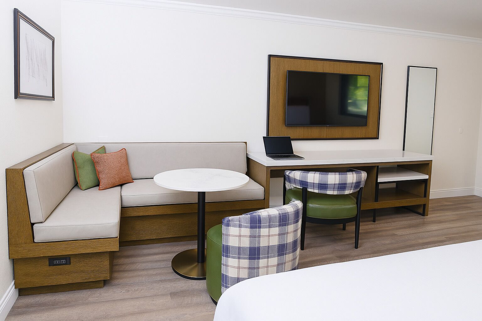 Ein Hotelzimmer mit einer Couch, einem kleinen runden Tisch, einem Schreibtisch mit Stuhl, einem Bett und einem Fernseher.