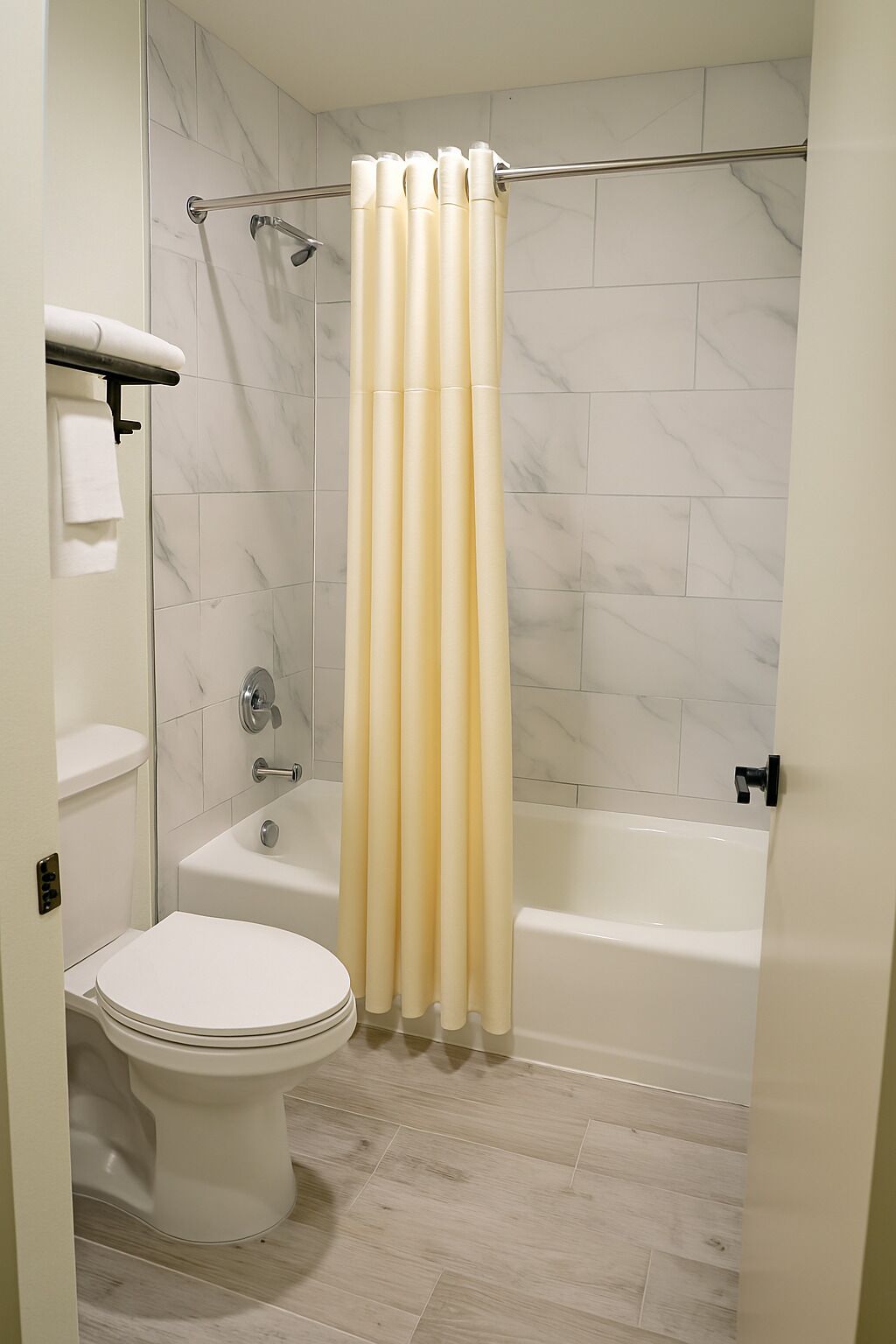 Et badeværelse med toilet, badekar og bruseforhæng.