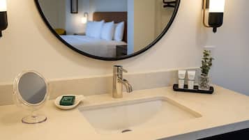 A hotel bathroom with a large mirror, a sink, and toiletries.