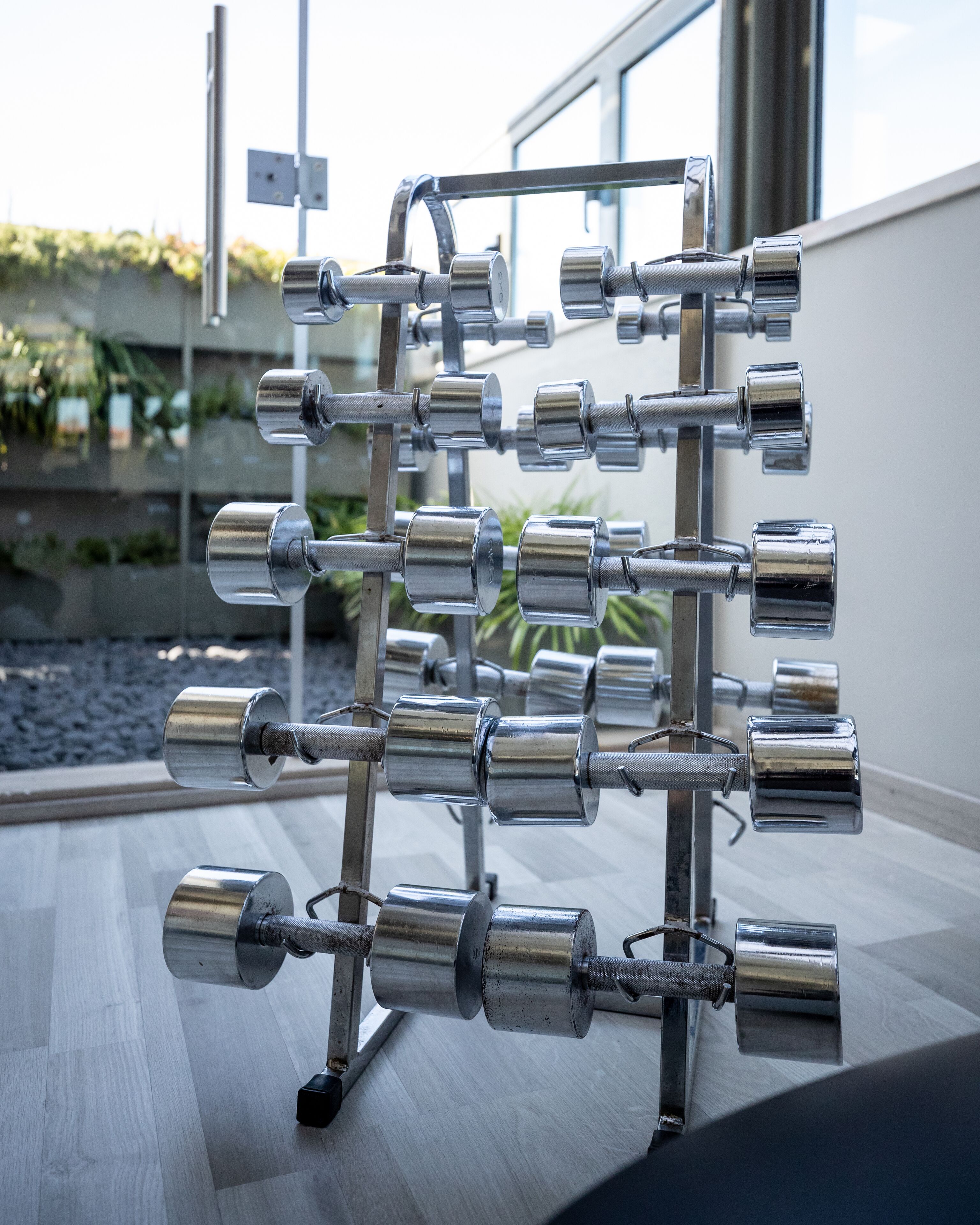 A metal rack with multiple cylindrical objects, likely weights, in an indoor setting with a window in the background.