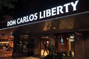 The exterior of a hotel named "Dom Carlos Liberty" with a well-lit entrance and a visible number "13" on the building.