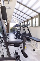 Una palestra con attrezzature per esercizi, tra cui tapis roulant e macchinari per pesi, sotto una copertura in vetro.