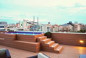 A rooftop terrace with a pool, steps, and seating areas.