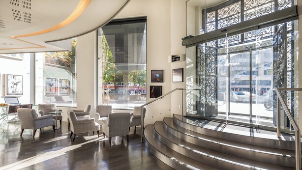 Un vestíbulo moderno con escalera, zona de estar y amplias ventanas.
