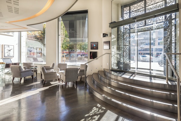 Un vestíbulo moderno con escalera, zona de estar y amplias ventanas.