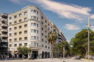 Um hotel de vários andares com fachada curva, varandas e uma placa indicando que é um hotel.
