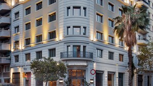 Un hotel de varios pisos con fachada curva, balcones y entrada a nivel de calle.