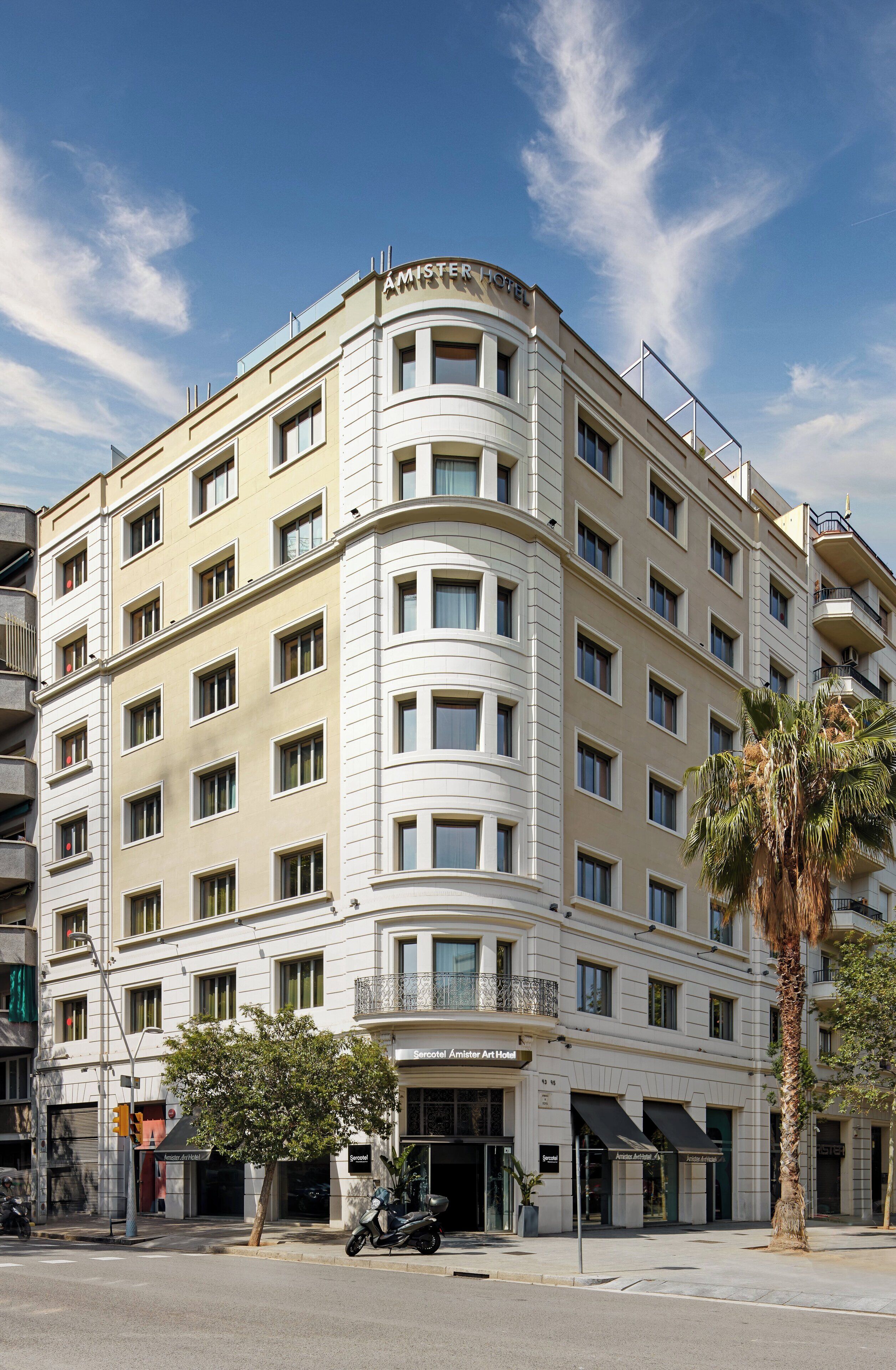A multi-story hotel with a curved facade, large windows, and a palm tree in front.