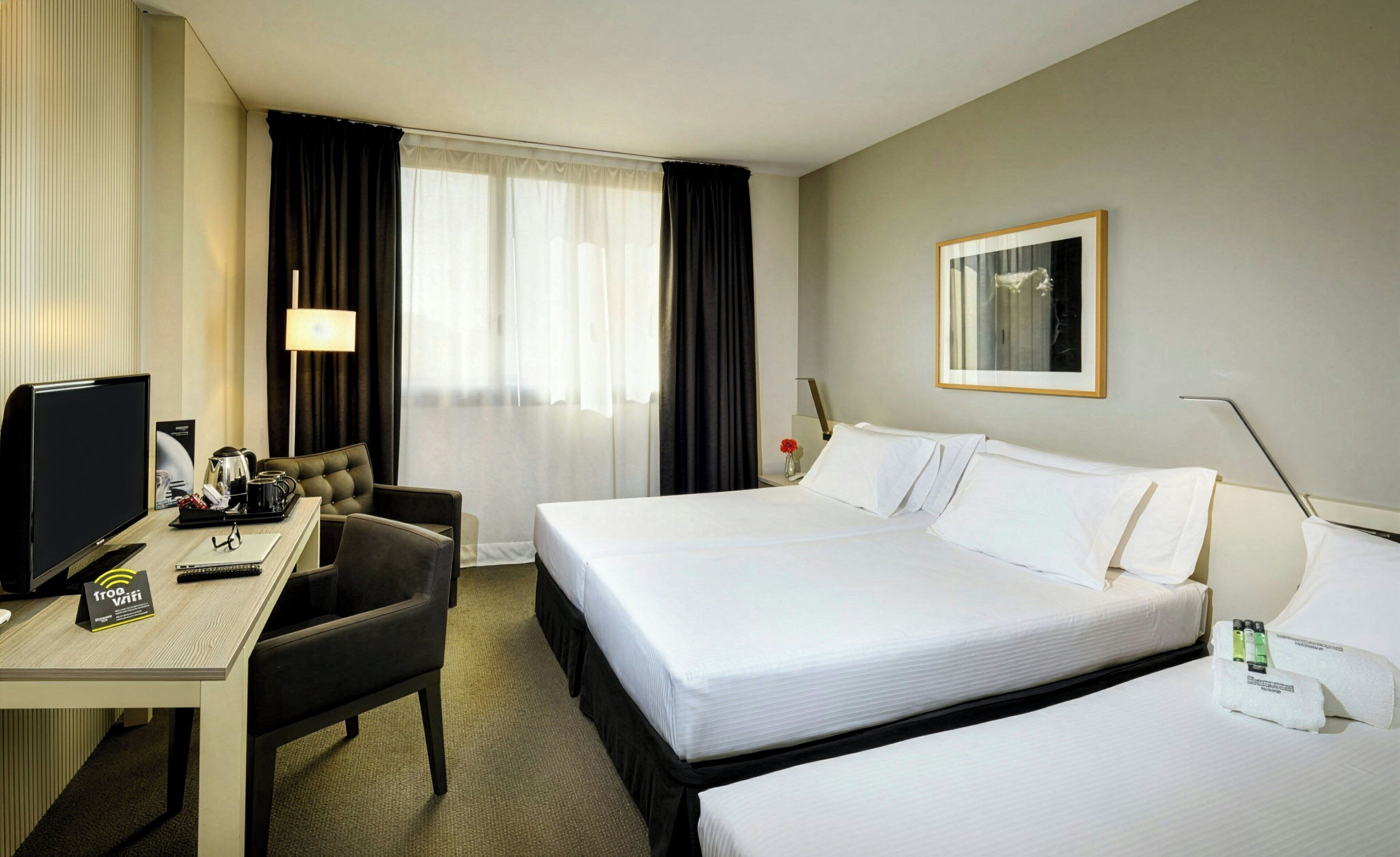 Una habitación de hotel con una cama, un escritorio con computadora, una silla y un televisor.