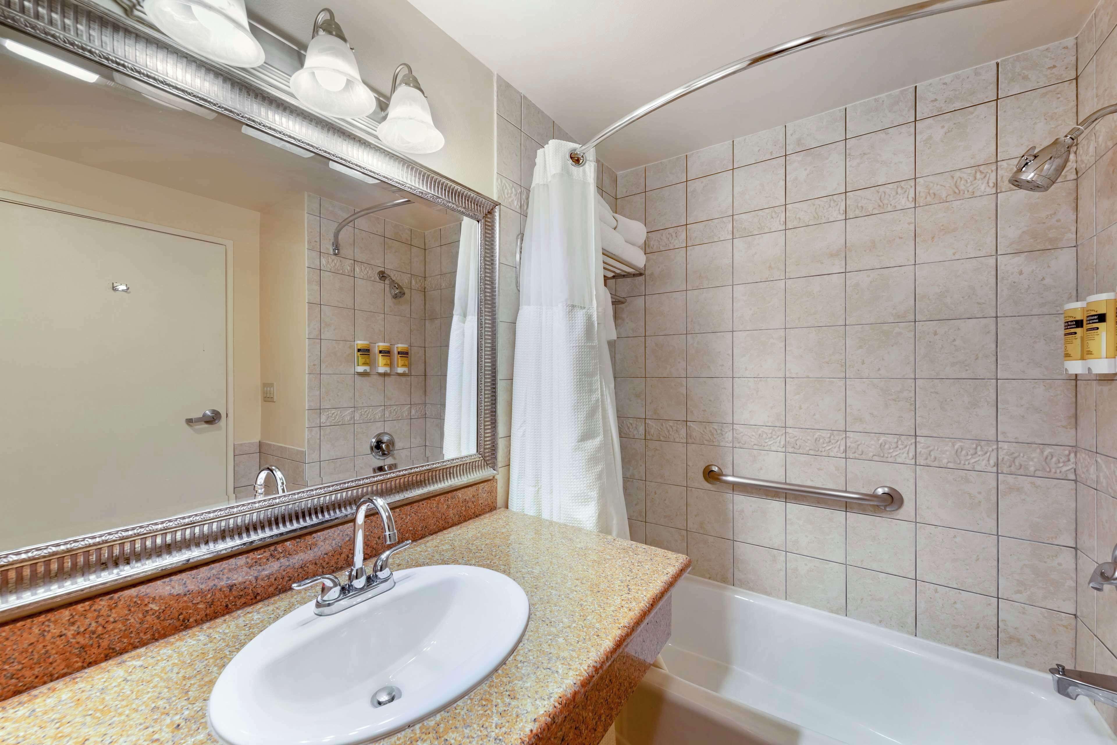 Un baño con lavamanos, espejo, ducha y bañera.