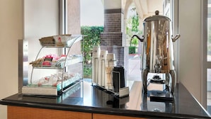 A coffee station with a coffee grinder and a display of coffee pods and sugar packets. - Best Western Plus Country Park Hotel (Tehachapi)
