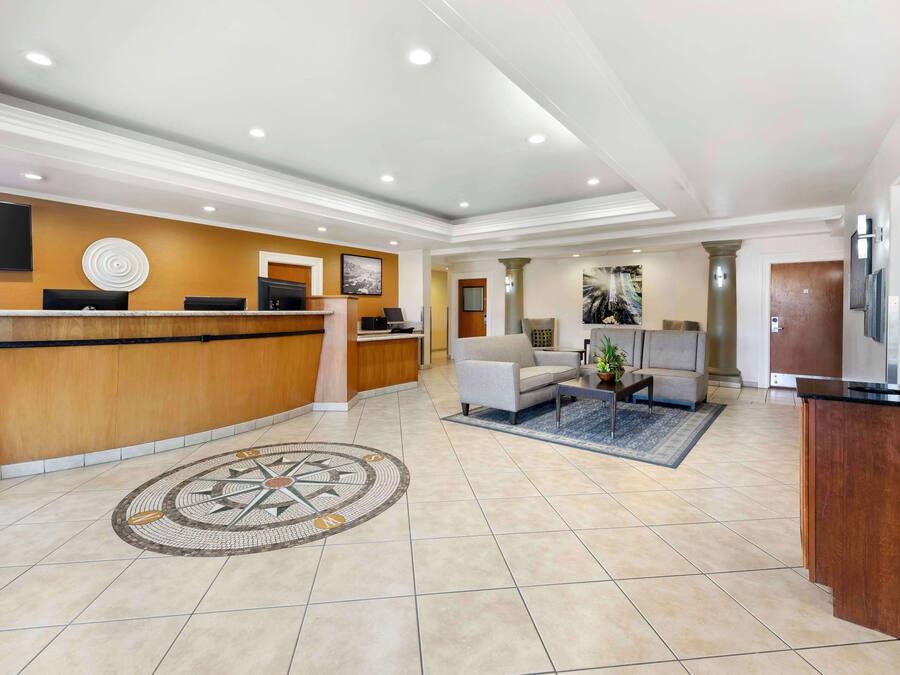 A hotel lobby with a reception desk, seating area, and a large decorative rug.