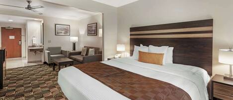 Habitación de hotel con una cama grande, un escritorio, una silla, un sofá y un ventilador de techo.