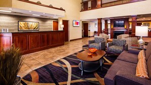 A hotel lobby with a reception desk, seating area, and a fireplace.