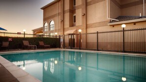 A swimming pool with lounge chairs and a fence.