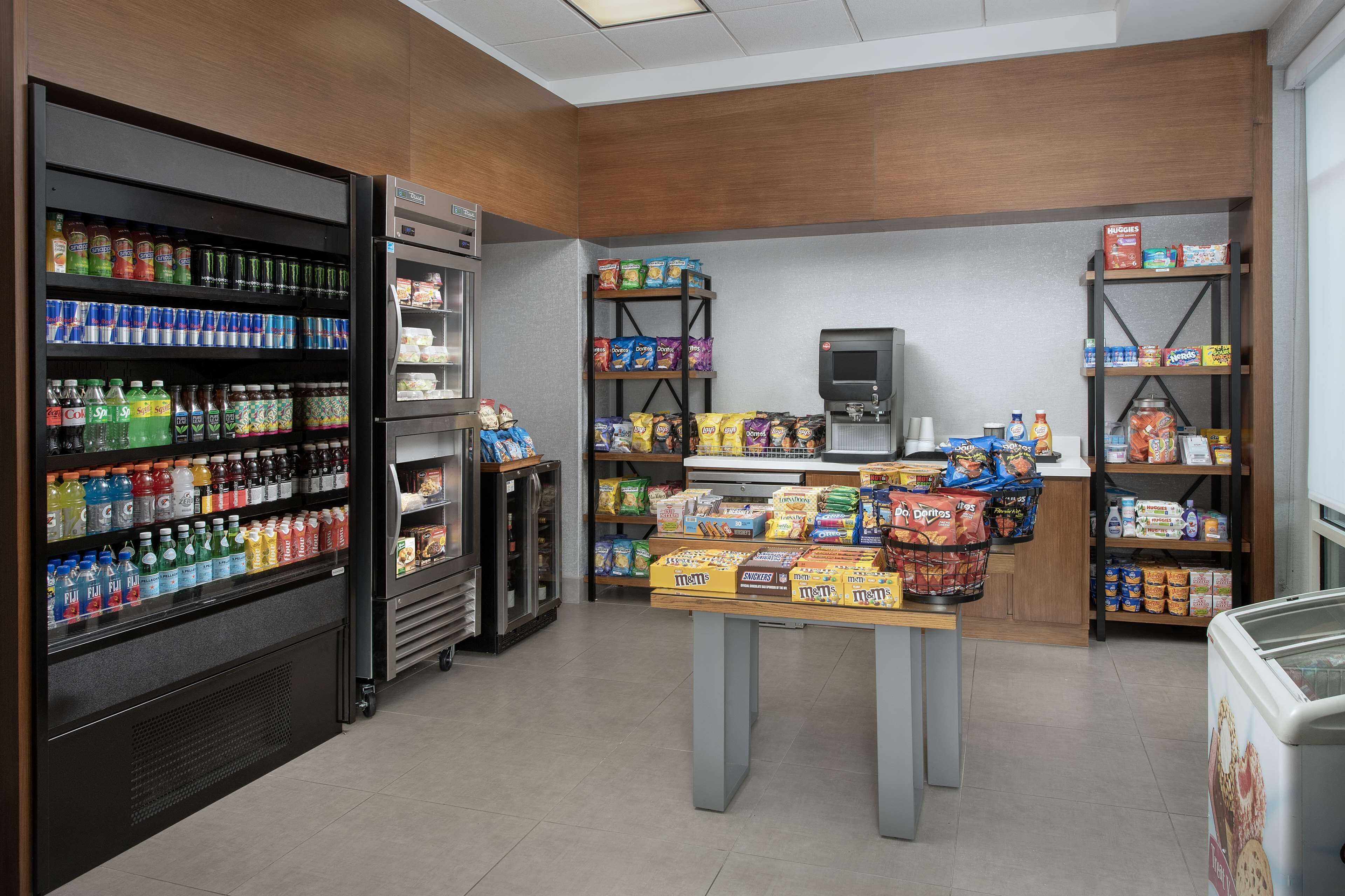 A grocery store interior with refrigerated sections, shelves stocked with snacks, and a self-serve beverage machine.
