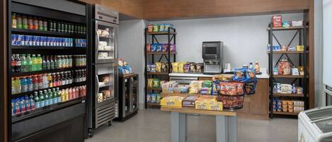 A grocery store interior with refrigerated sections, shelves stocked with snacks, and a self-serve beverage machine.