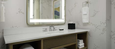 A bathroom with a white vanity, a large mirror, and a towel rack.
