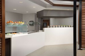 A modern breakfast bar with glass display cases and a chalkboard menu. - Embassy Suites by Hilton Dulles North Loudoun (Ashburn)