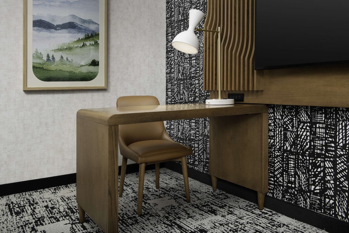 Una habitación moderna con escritorio, silla y un cuadro enmarcado con un paisaje.