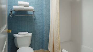 A bathroom with a toilet, a towel rack with towels, and a shower curtain.
