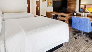 A hotel room with two beds, a TV, a desk with a chair, and a microwave.