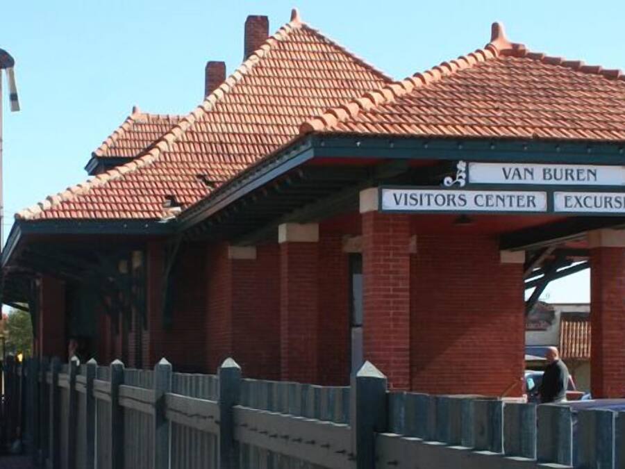 A brick building with a red-tiled roof labeled "Van Buren Visitors Center Excursion Train."