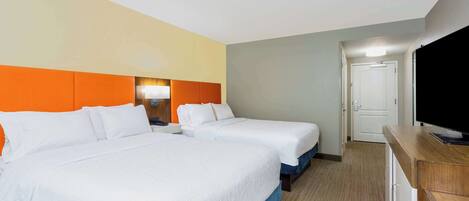 A hotel room with two beds, a TV, and a desk.
