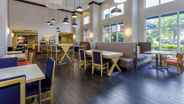 A spacious restaurant with high ceilings, large windows, and modern lighting. Tables and chairs are arranged for dining. - Hampton Inn & Suites Tallahassee I-10/Thomasville Road, FL (Tallahassee)