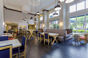 A spacious restaurant with high ceilings, large windows, and modern lighting. Tables and chairs are arranged for dining. - Hampton Inn & Suites Tallahassee I-10/Thomasville Road, FL (Tallahassee)
