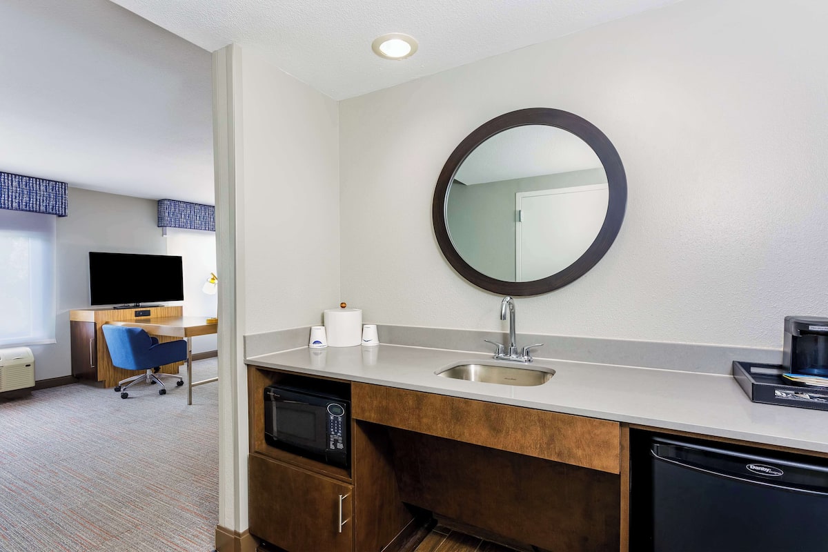 A hotel bathroom with a sink, mirror, and a microwave.