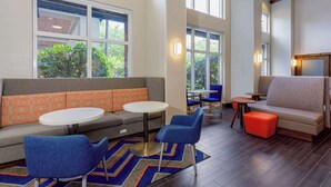 A modern lounge area with a sofa, chairs, a round table, and a bench. - Hampton Inn & Suites Tallahassee I-10/Thomasville Road, FL (Tallahassee)