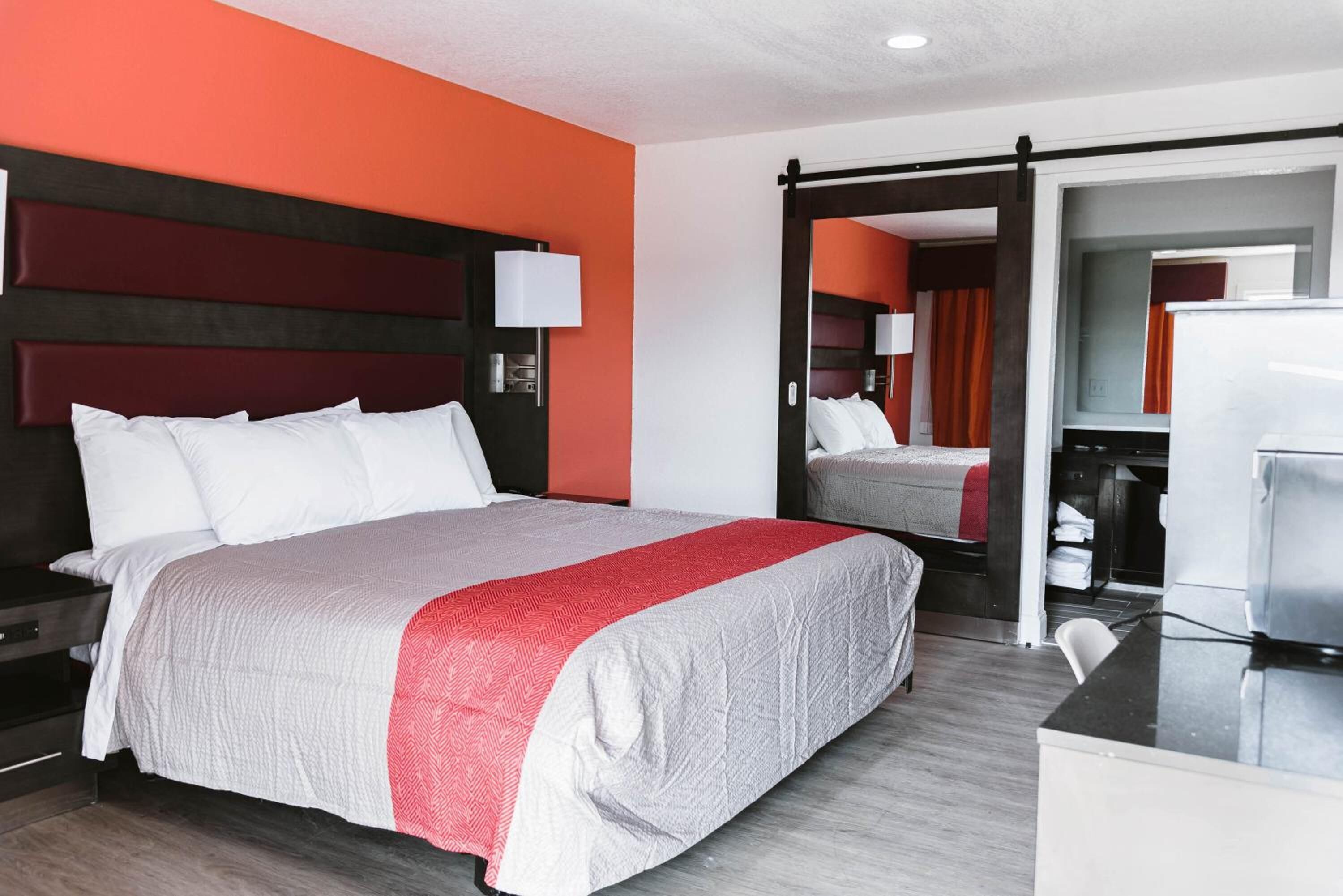 A hotel room with a large bed, a desk, and a mirror.