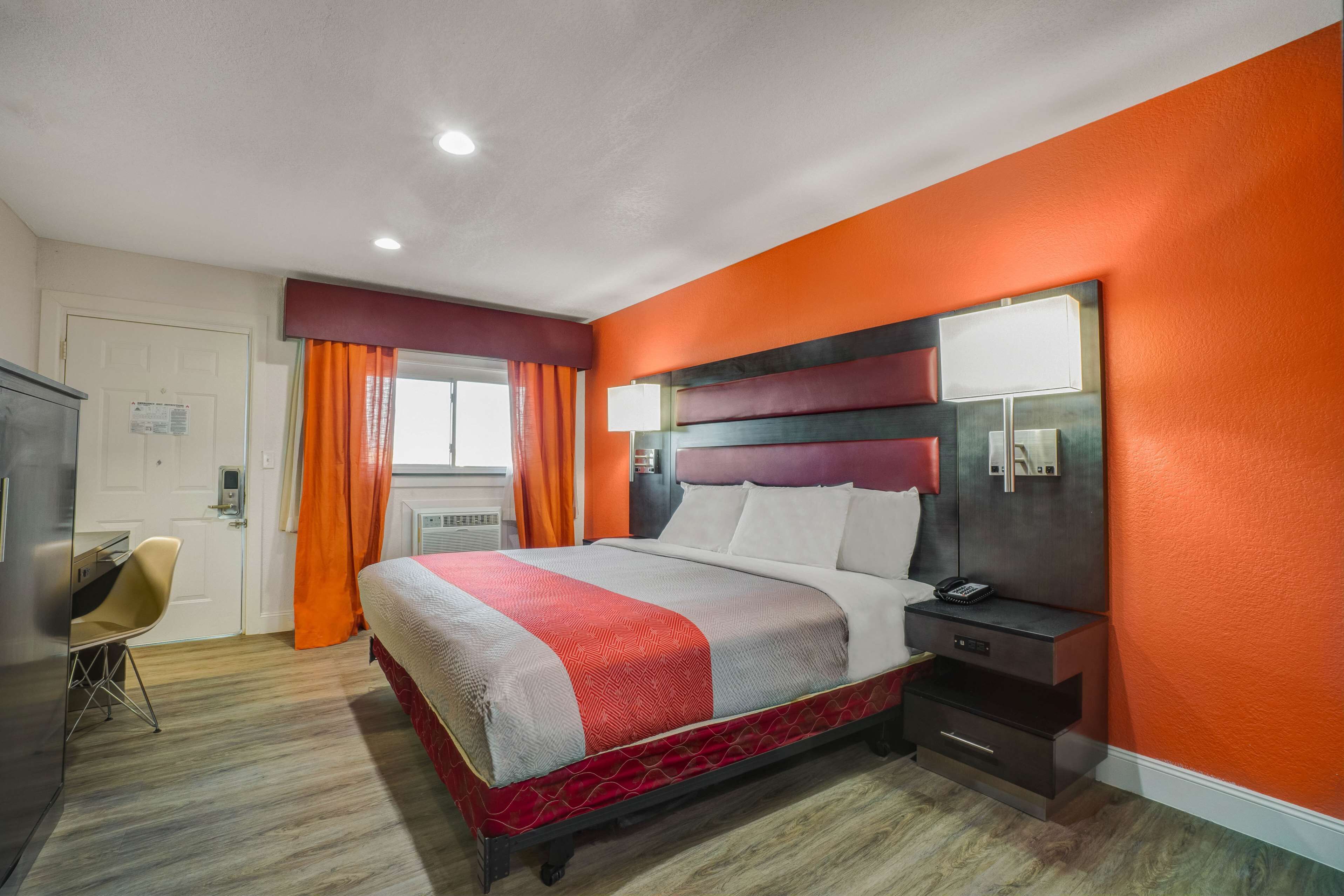 Quarto de hotel com uma cama, uma escrivaninha e uma cadeira.