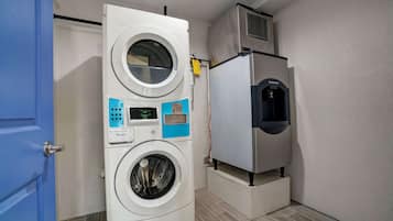 Une petite buanderie équipée d’un lave-linge et d’un sèche-linge à chargement frontal, d’un petit réfrigérateur et d’une porte bleue.