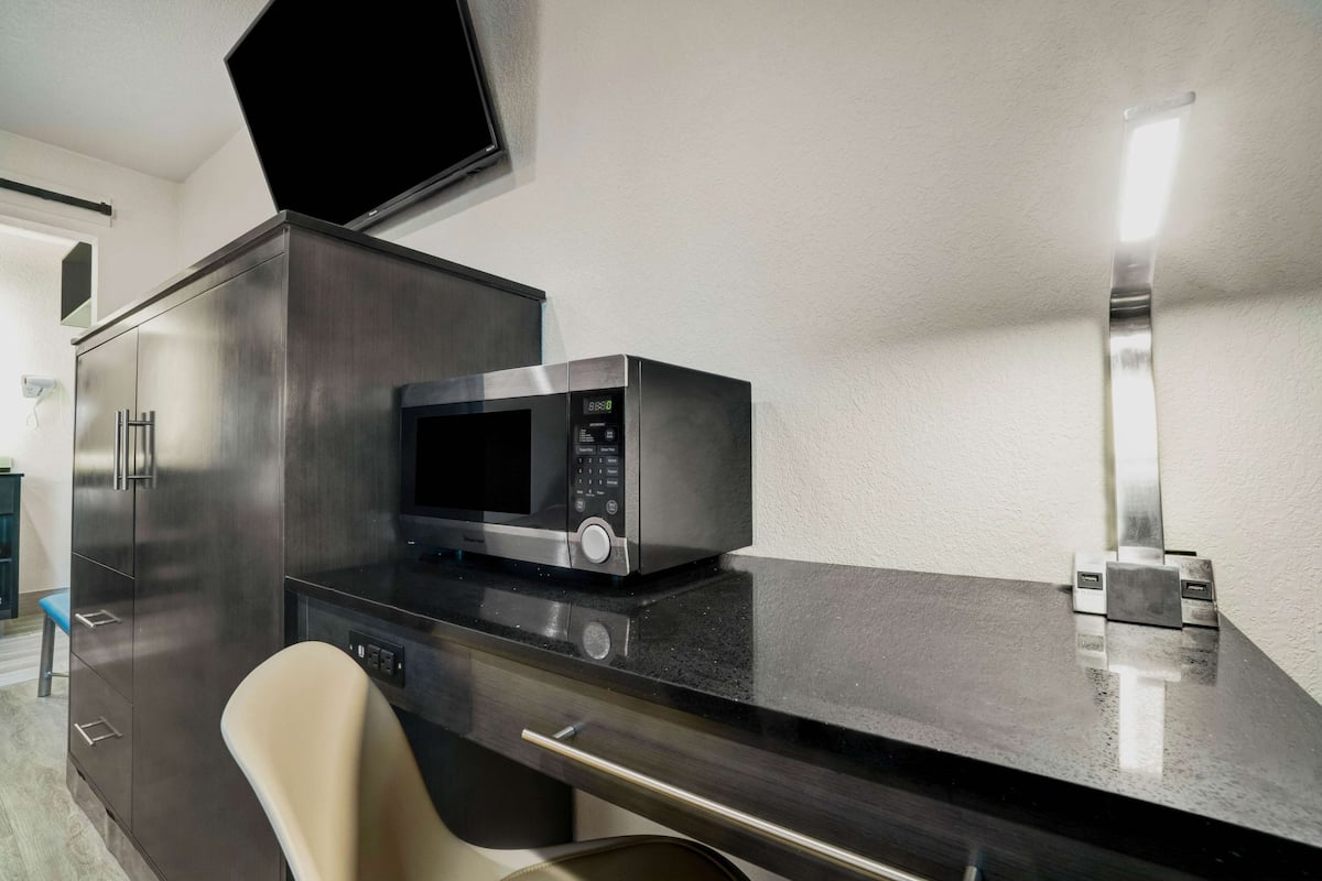 A modern kitchen with a microwave, a cabinet, and a chair.