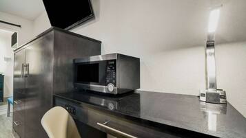 A modern kitchen with a microwave, a cabinet, and a chair.