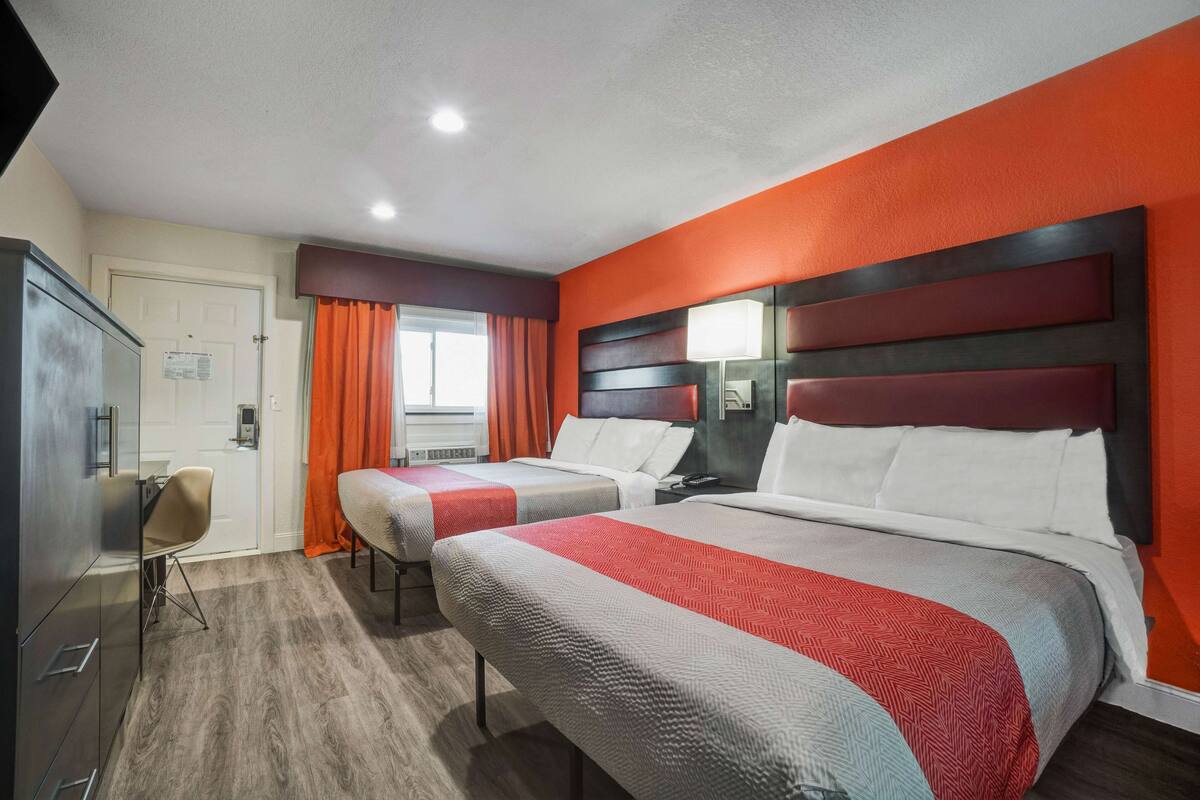 A hotel room with two beds, a desk, and a chair.