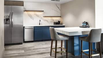 Una cucina moderna con zoccolo in marmo, elettrodomestici in acciaio inossidabile e un'isola centrale con sgabelli da bar.