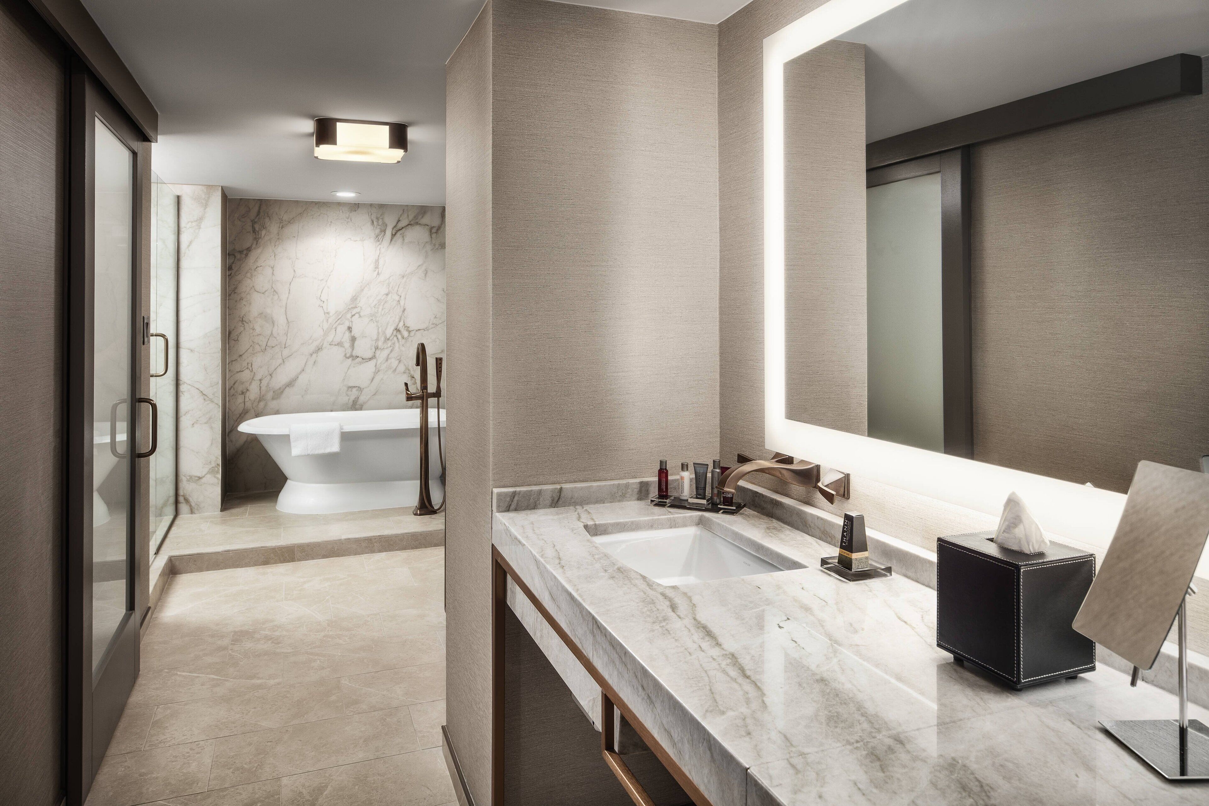 A modern bathroom with a freestanding bathtub, a large mirror, and a vanity with a marble countertop.