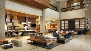 A spacious lobby with a bar area, seating arrangements, and a visible kitchen bar. - Louisville Marriott Downtown (Louisville)