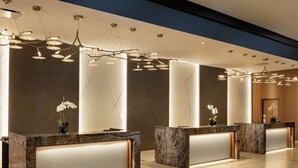 A reception area with marble counters, modern pendant lighting, and potted orchids. - Louisville Marriott Downtown (Louisville)
