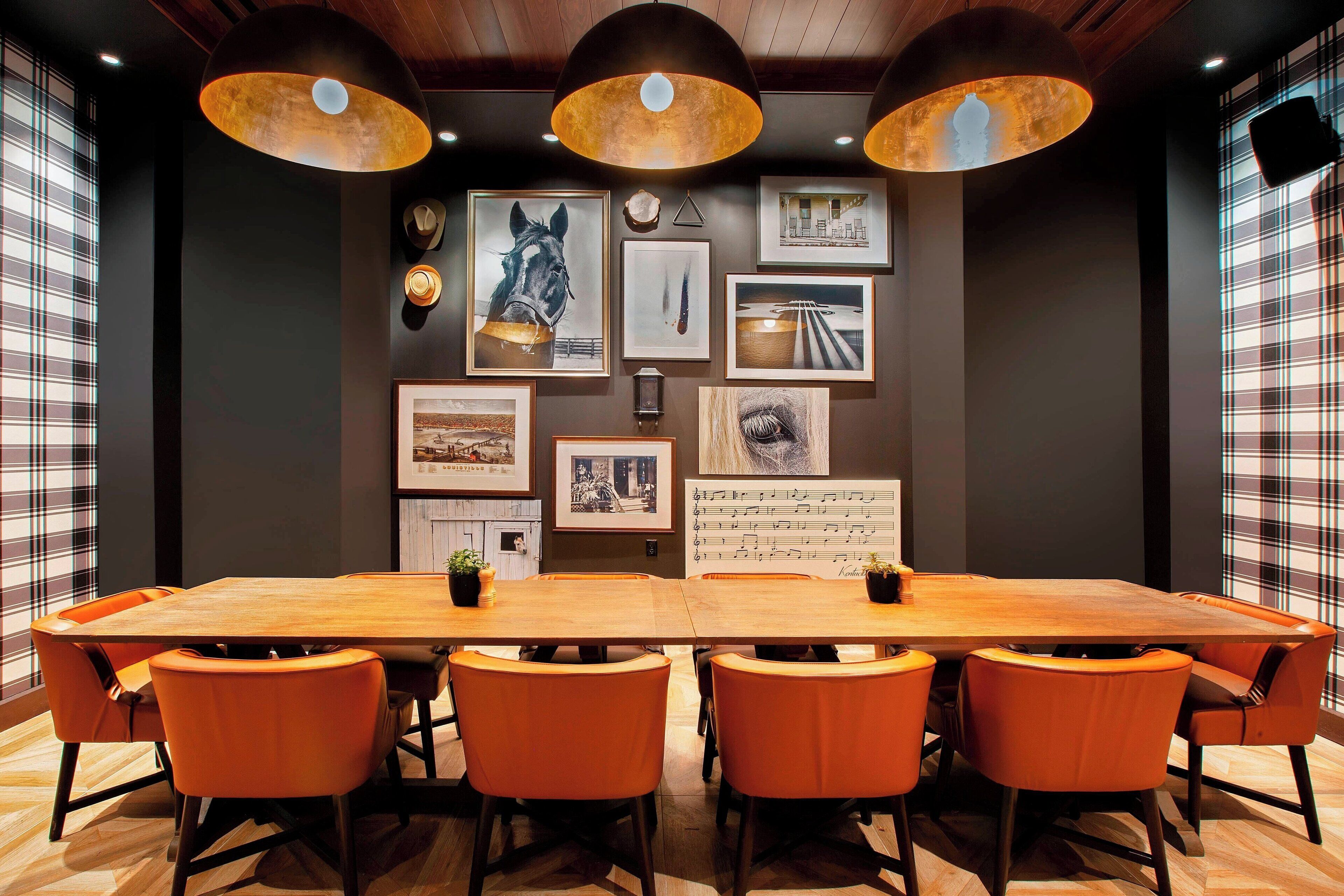 A conference room with a large wooden table, orange chairs, and pendant lighting.